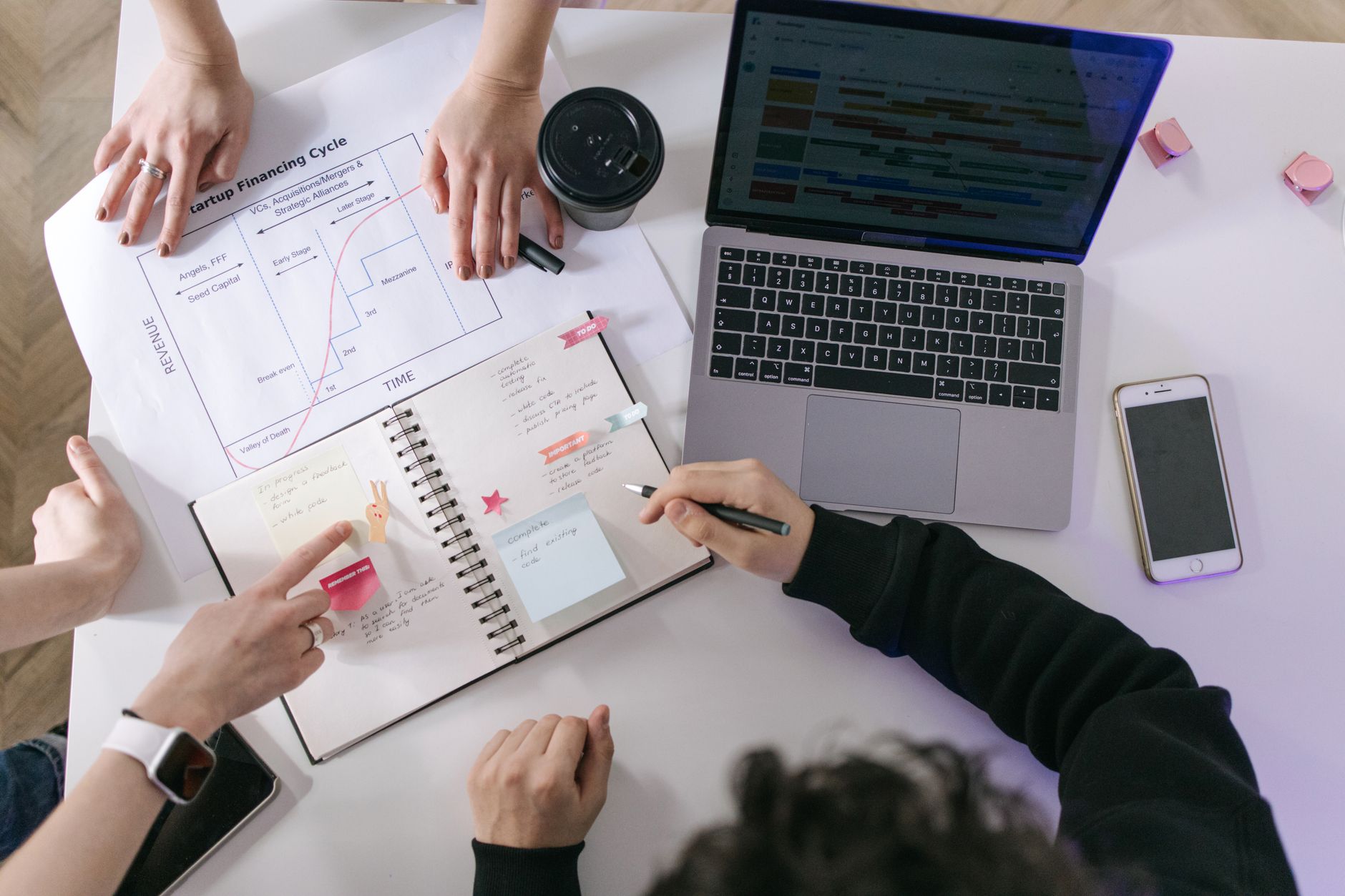 caderno, celular e notebook lado a lado sobre uma mesa
