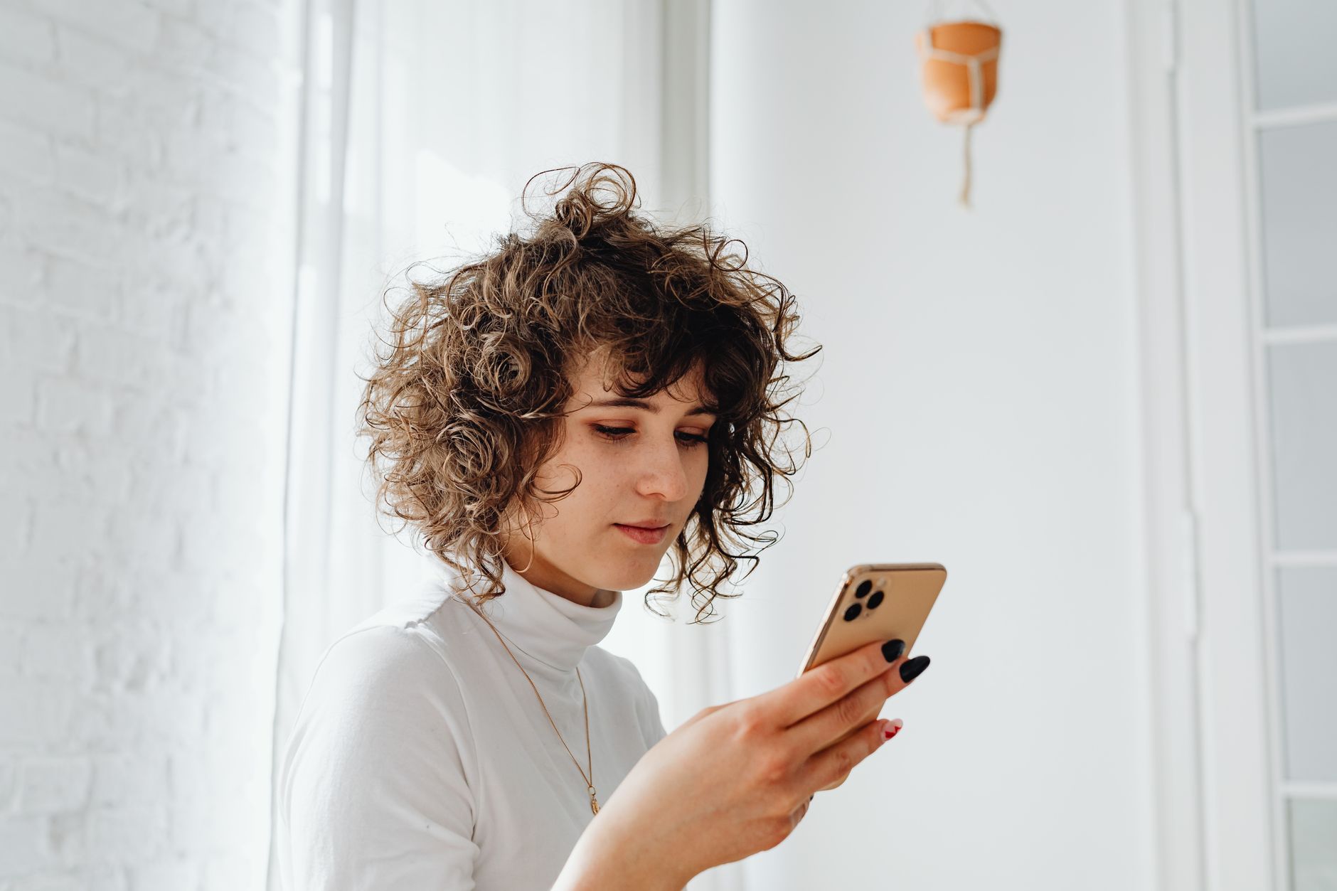 mulher olhando mensagens no celular na cozinha
