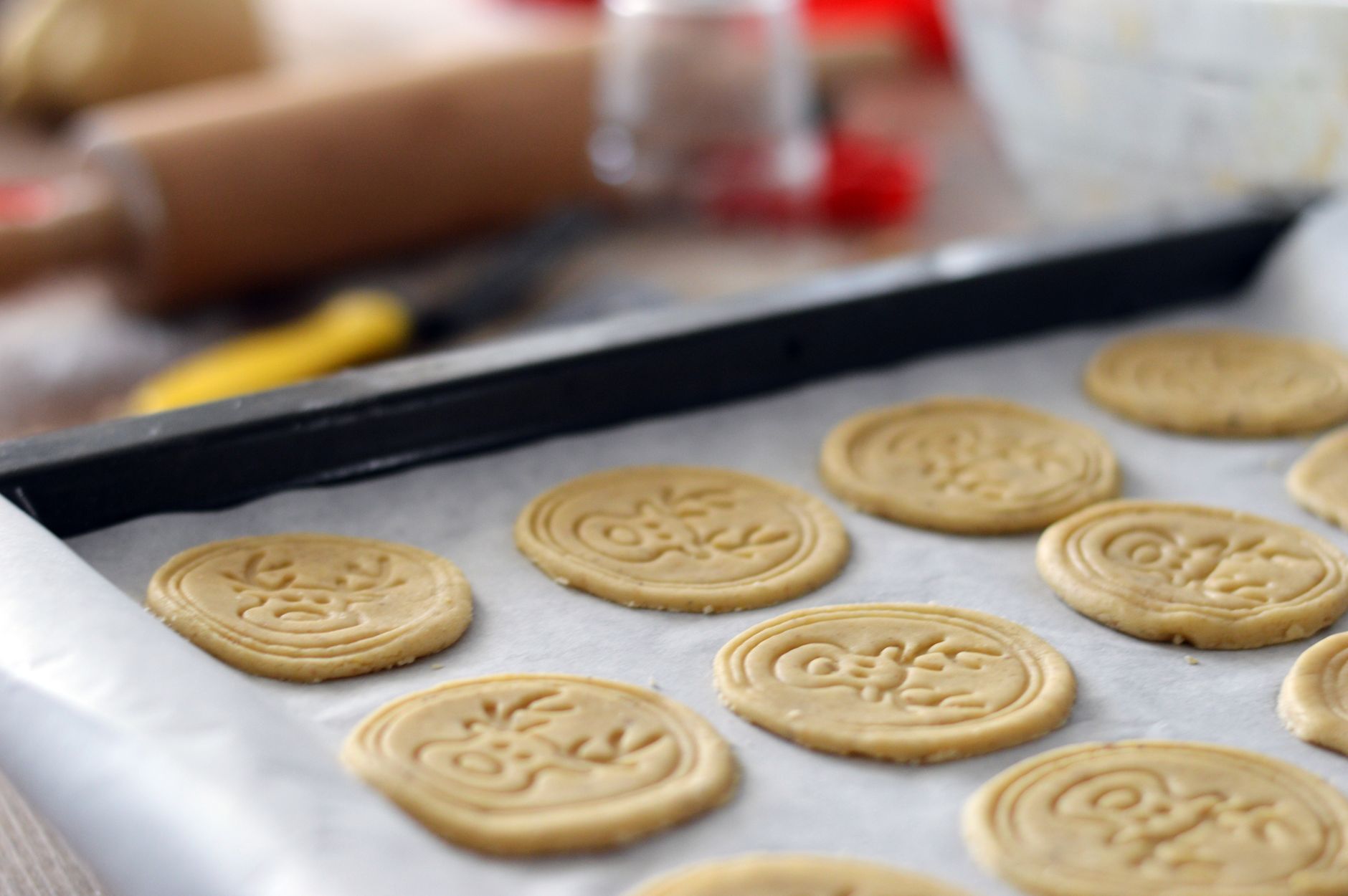 biscoitos natalinos sendo decorados sobre uma mesa de cozinha