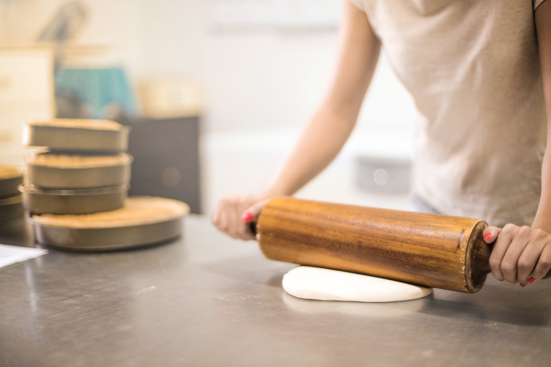 confeiteira trabalhando na cozinha com vários bolos na bancada