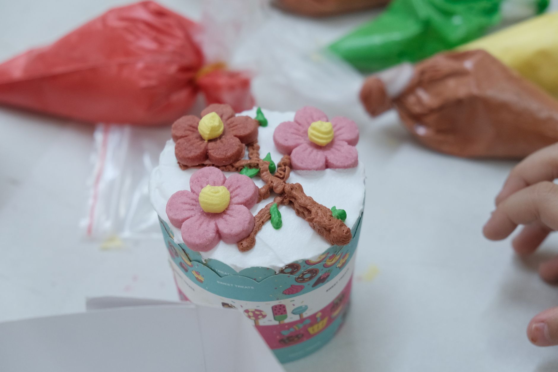 mãos decorando um bolo com saco de confeitar